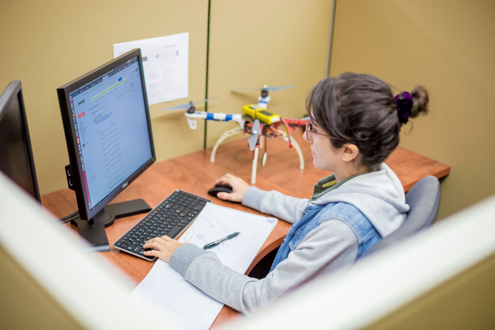 Female student with hair in a bun sitting at a computer and working